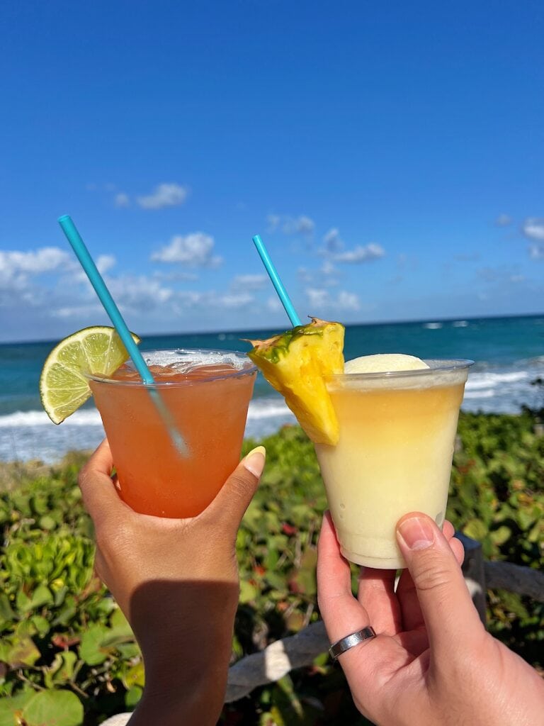 Close-up of colorful cocktails at Jupiter Beach Resort & Spa, with a blurry beach background, highlighting a refreshing tropical drink experience.